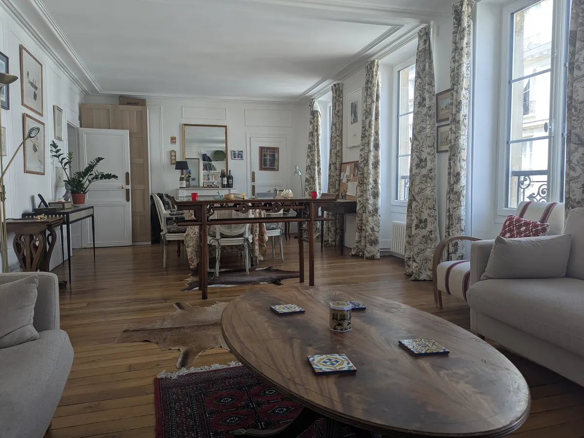 Salon d'un appartement parisien : parquet ancien, moulures et grandes fenêtres