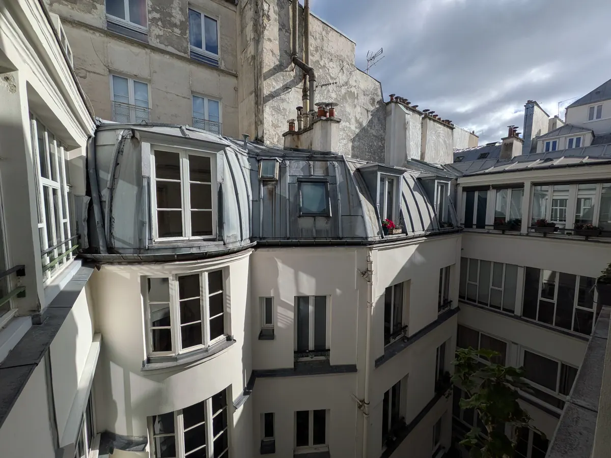 Cour intérieure d'un immeuble parisien, façades claires et toits en zinc